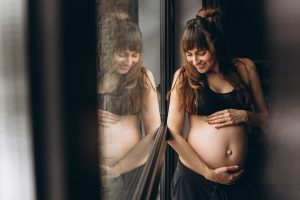 pregnant-woman-standing-by-window_1303-12880